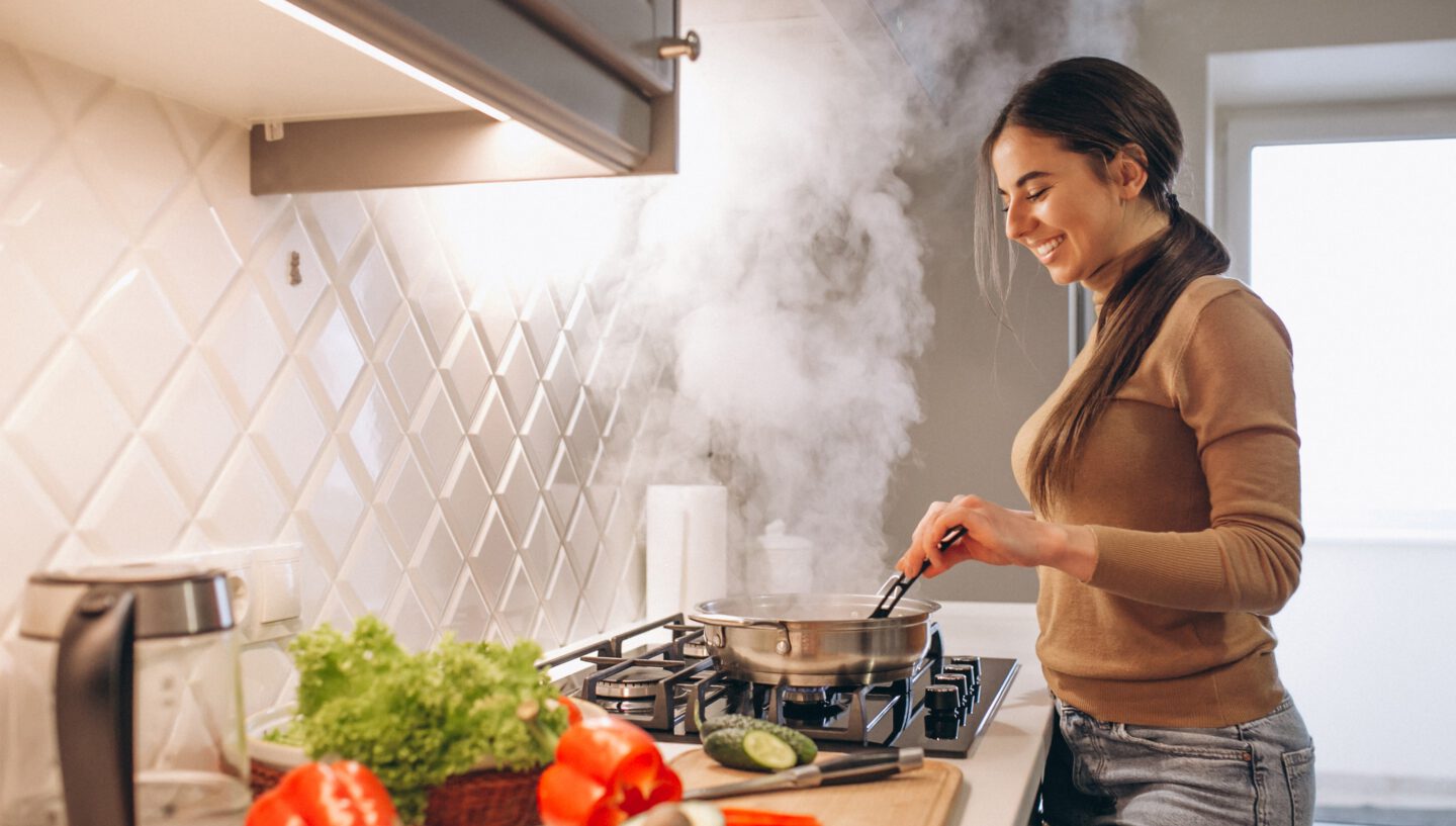 Bild von einer Frau am kochen mit viel Dampf