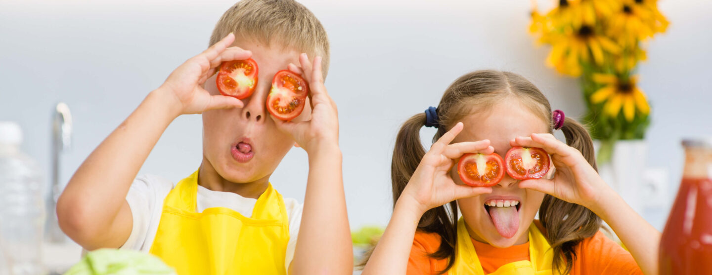 Zwei Kinder albern mit Tomaten rum und halten sich diese vor die Augen.