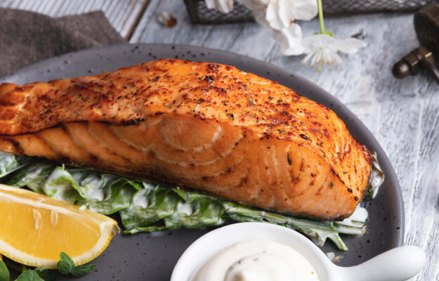 Aufnahme eines Fischfilets auf Salat mit Zitrone und Remoulade.