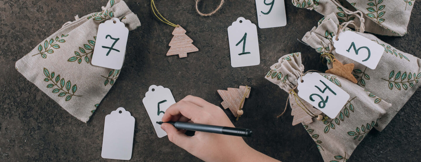 Eine Hand schreibt Zahlen und bastelt einen Adventskalender aus der Küche.