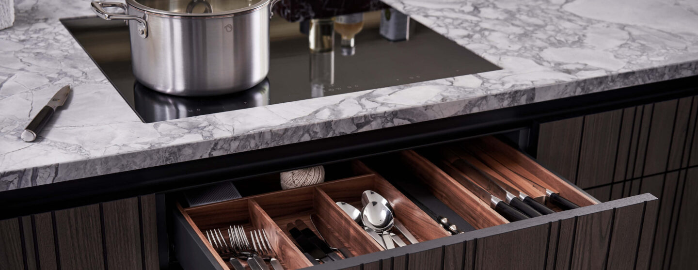 Offene Schublade unter einem Kochfeld in einer Leicht Küche.