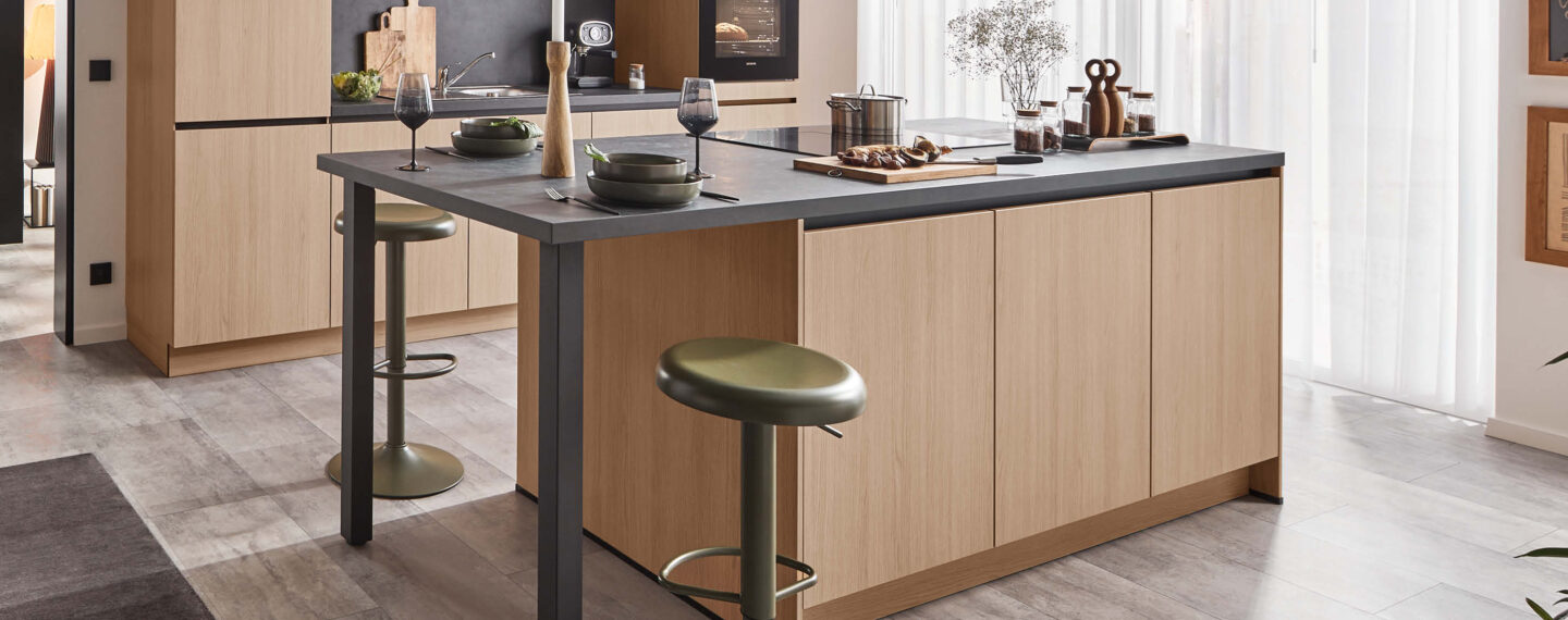 Moderne Küche mit grifflosen Holzfronten, Kochinsel und schwarzer Steinarbeitsplatte von Häcker Küchen.
