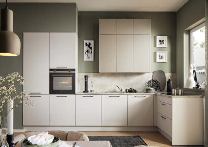 Freundliche Wohnküche mit grün gestrichener Wand, neutralen Fronten und modernem Dekor.