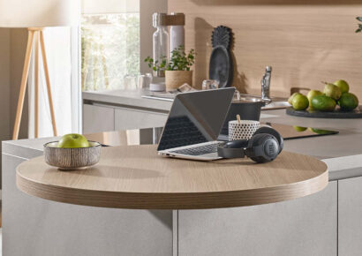 Multifunktionale Küche planen mit runder Ansetztisch-Lösung an der Kücheninsel, genutzt als Arbeitsplatz mit Laptop in moderner Wohnküche.