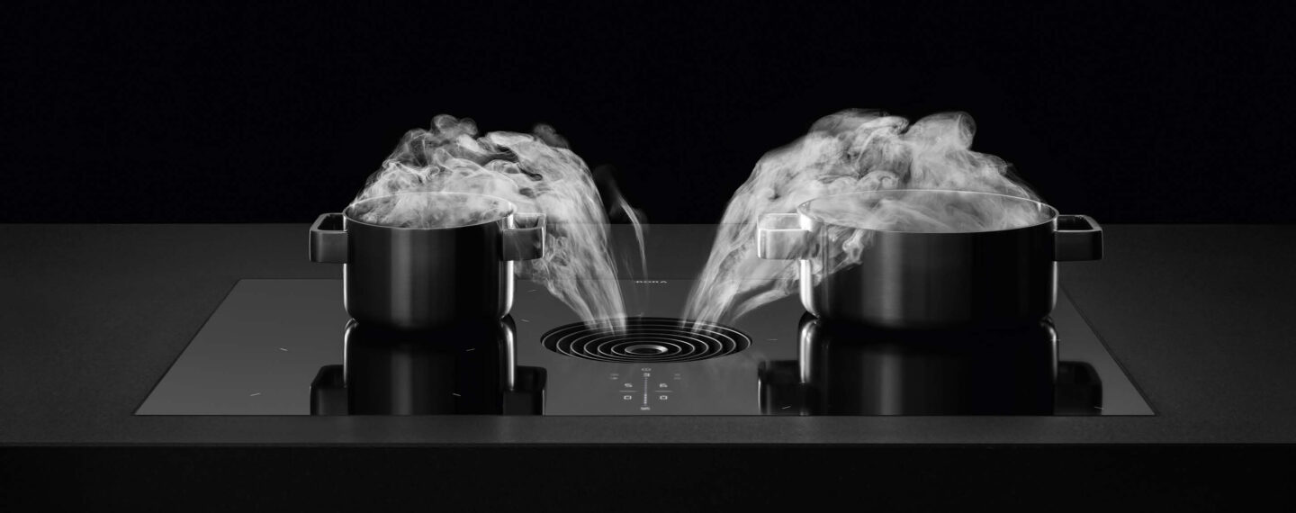 BORA Kochfeldabzugssysteme – Schwarze Töpfe auf schwarzer Kochplatte mit schwarzem Hintergrund.