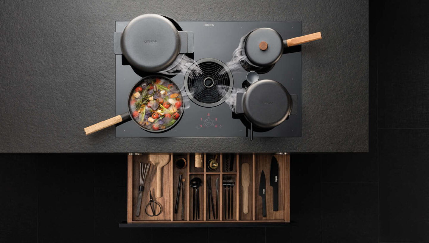 Vogelperspektive auf ein Kochfeld von BORA mit Kochfeldabzug in der Mitte. BORA Kochfeldabzugssysteme