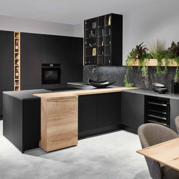 Moderne T-Küche in schwarz mit hellen Eichenholzakzenten und Steinarbeitsplatte bei Küchenstyle Lübeck.