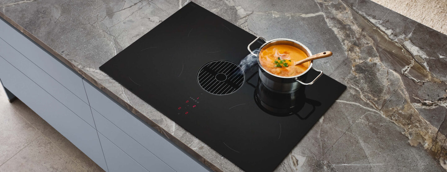 Multifunktionale Küche planen mit modernem Induktionskochfeld und integriertem Dunstabzug auf robuster Arbeitsplatte.