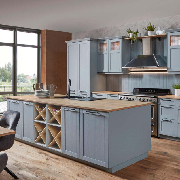 Graue Nobilia Landhausküche mit Kücheninsel, Holzarbeitsplatte und integriertem Weinregal – stilvolle Küchenplanung von Küchenstyle.