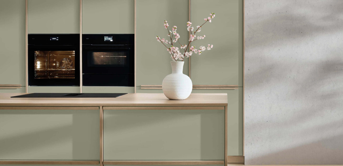 Moderne Nobilia Küche in Salbeigrün mit Holzarbeitsplatte, Einbaugeräten und minimalistischem Design – hochwertige Küchenplanung bei Küchenstyle.