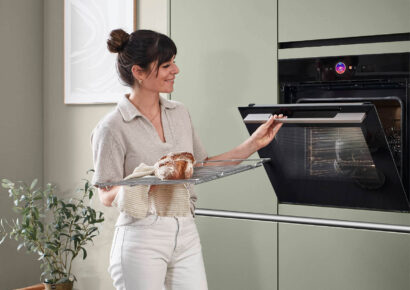 Bild von nobilia: Frau mit Brot auf Ofenrost in der Hand öffnet Backofen